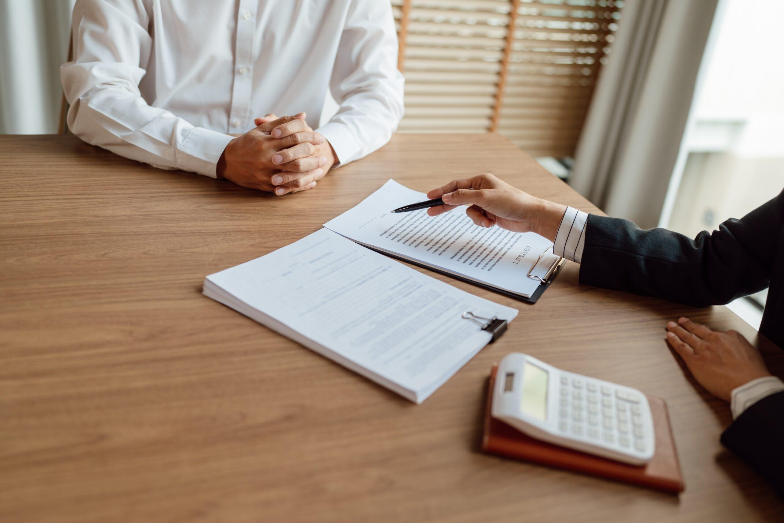 Two business professionals seated at a table, reviewing paperwork related to insurance claims.