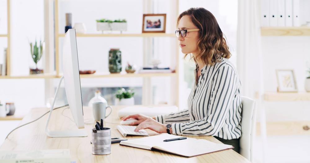 Woman working at a desktop computer in a home office